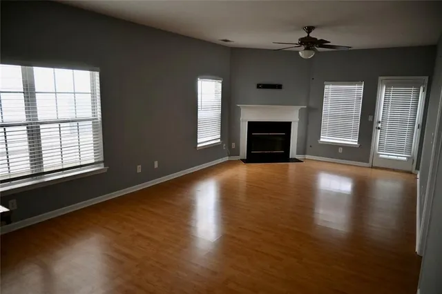 a view of a livingroom with wooden floor a fireplace and windows