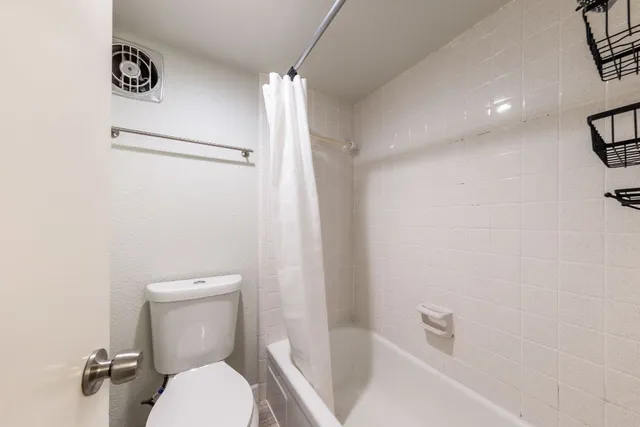 a white toilet sitting next to a bath tub