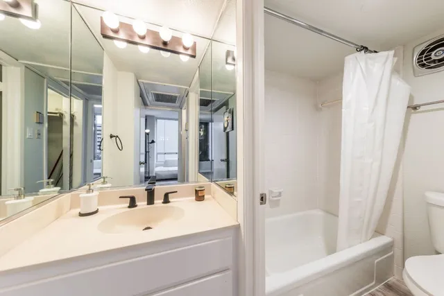 a bathroom with a tub shower sink and mirror