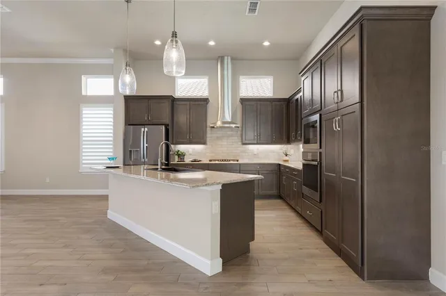 a view of a room with wooden floor chandeliers and kitchen view