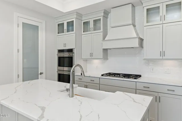 a kitchen with stainless steel appliances kitchen island a stove a sink and white cabinets