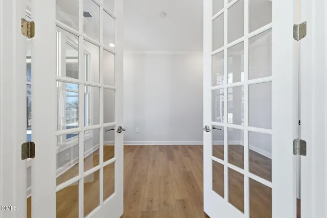 a view of an empty room with wooden floor and windows