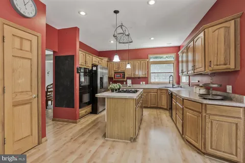 a kitchen with stainless steel appliances granite countertop a refrigerator a sink dishwasher a stove and white cabinets with wooden floor