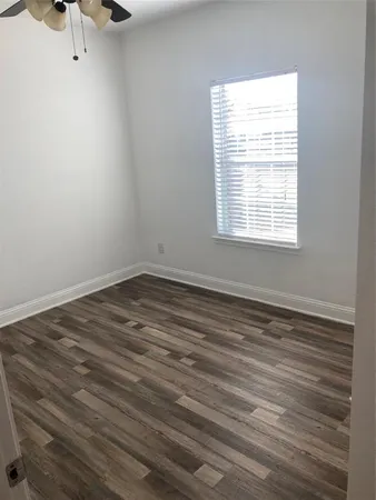 a view of a hallway with wooden floor and a bathroom