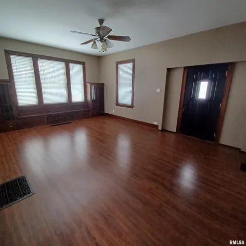 a view of empty room with wooden floor and fan