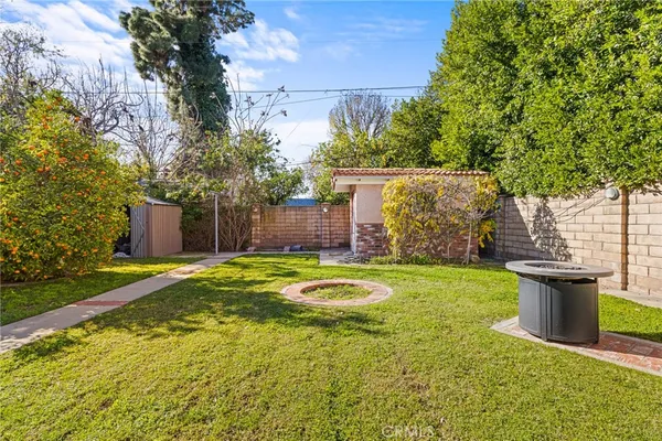a view of a backyard with plants and brick wall