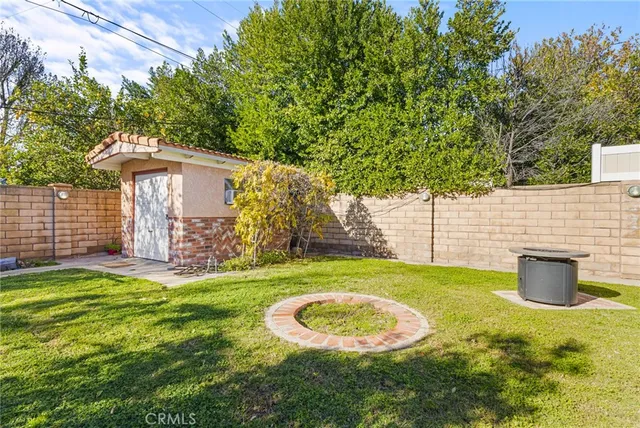 a view of a backyard with table and chairs potted plants and large tree