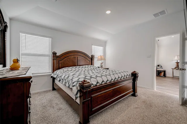 a bed sitting in a bedroom next to a window with a dresser