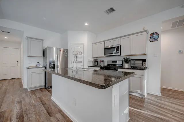 a kitchen with stainless steel appliances granite countertop a refrigerator a stove top oven a sink and dishwasher