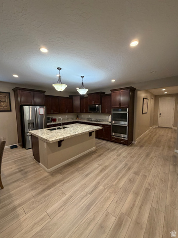 118 Tram Rock Rd. Lake Point, UT 84074 - Photo 10 of 34 Kitchen featuring dark wood cabinetry, a central island with a light-toned countertop, stainless steel appliances, and wood-finish flooring