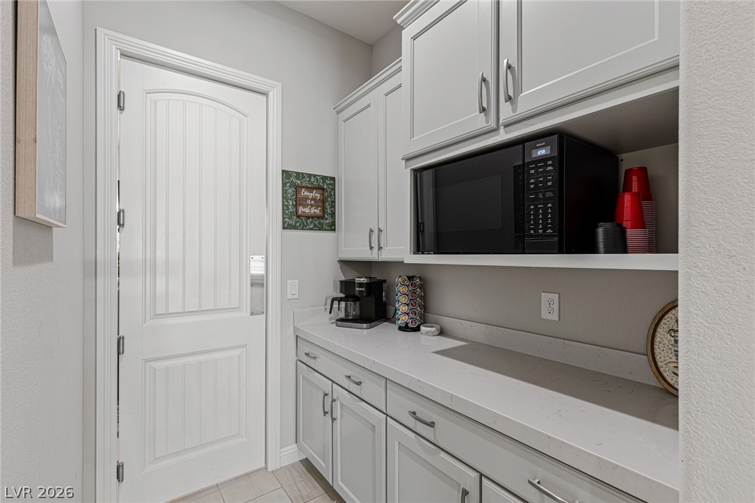 7036 Arabian Ridge Street Las Vegas, NV 89131 - Photo 24 of 64 Butler's Pantry with pivot door, microwave, and upper and lower cabinetry.