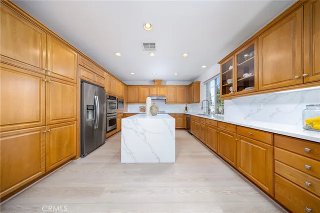 a kitchen with stainless steel appliances granite countertop a refrigerator a stove and a sink with cabinets