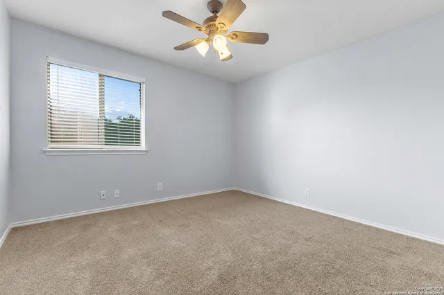 an empty room with a window and a fan