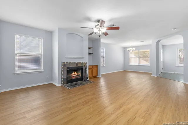 a view of an empty room with wooden floor fireplace and a window