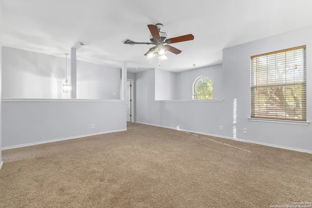 an empty room with windows and fan