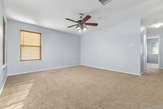 an empty room with windows and fan
