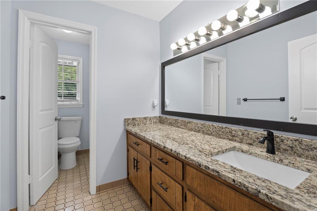 2827 Highway 138 Conyers, GA 30013 - Photo 24 of 32 a bathroom with a granite countertop sink and a toilet