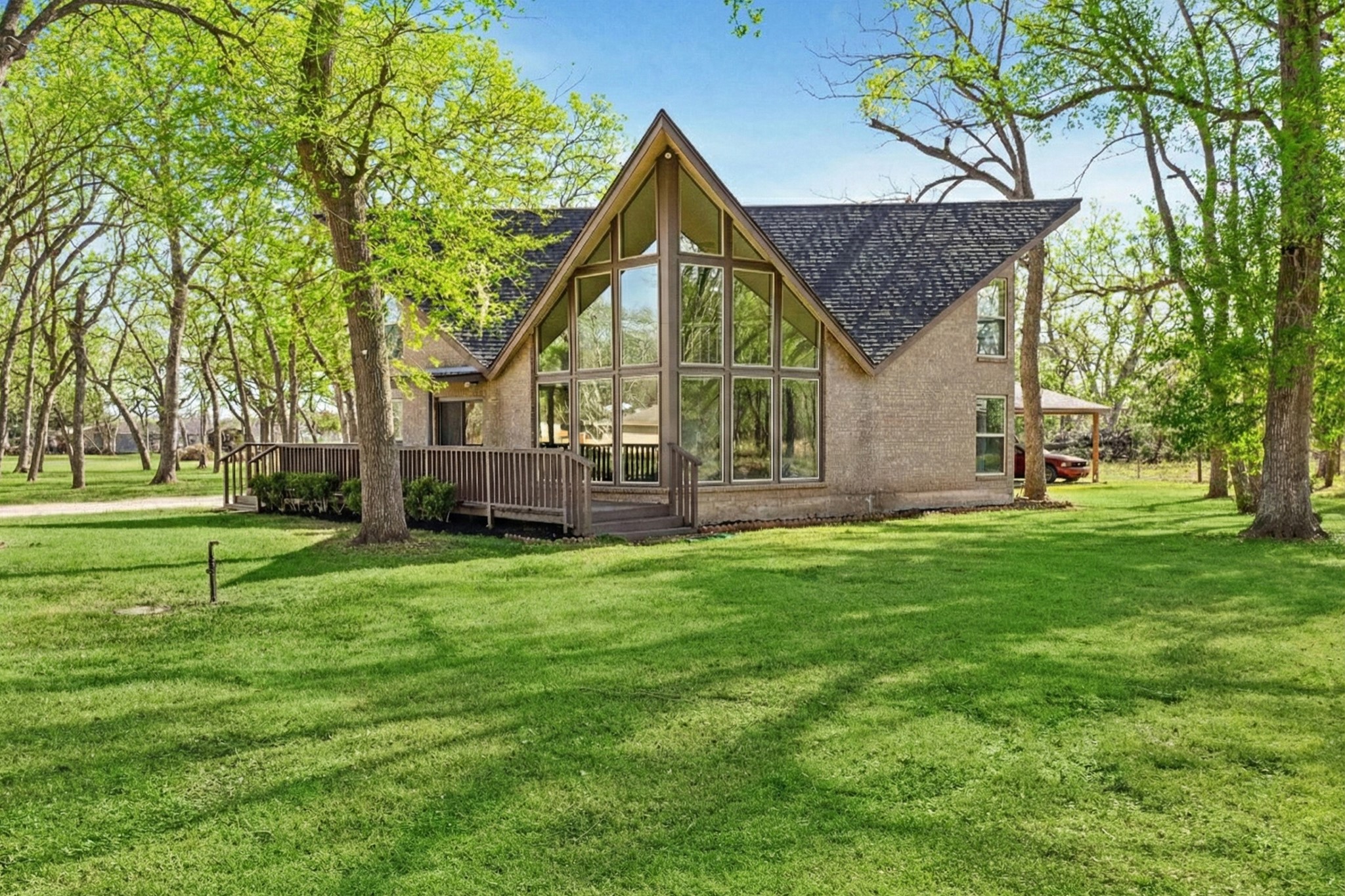 Close exterior angle emphasizing dramatic floor-to-ceiling windows, pitched roofline, and wooded backdrop.