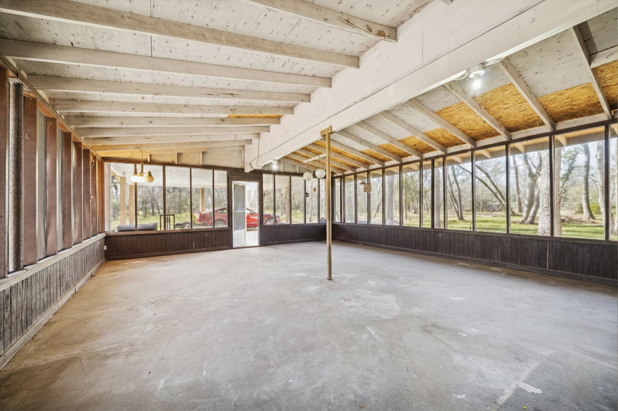 14311 Blidel Road Thompsons, TX 77469 - Photo 17 of 27 Enclosed covered patio or bonus space with exposed beams, concrete flooring, seating area, and expansive screened windows overlooking the property.