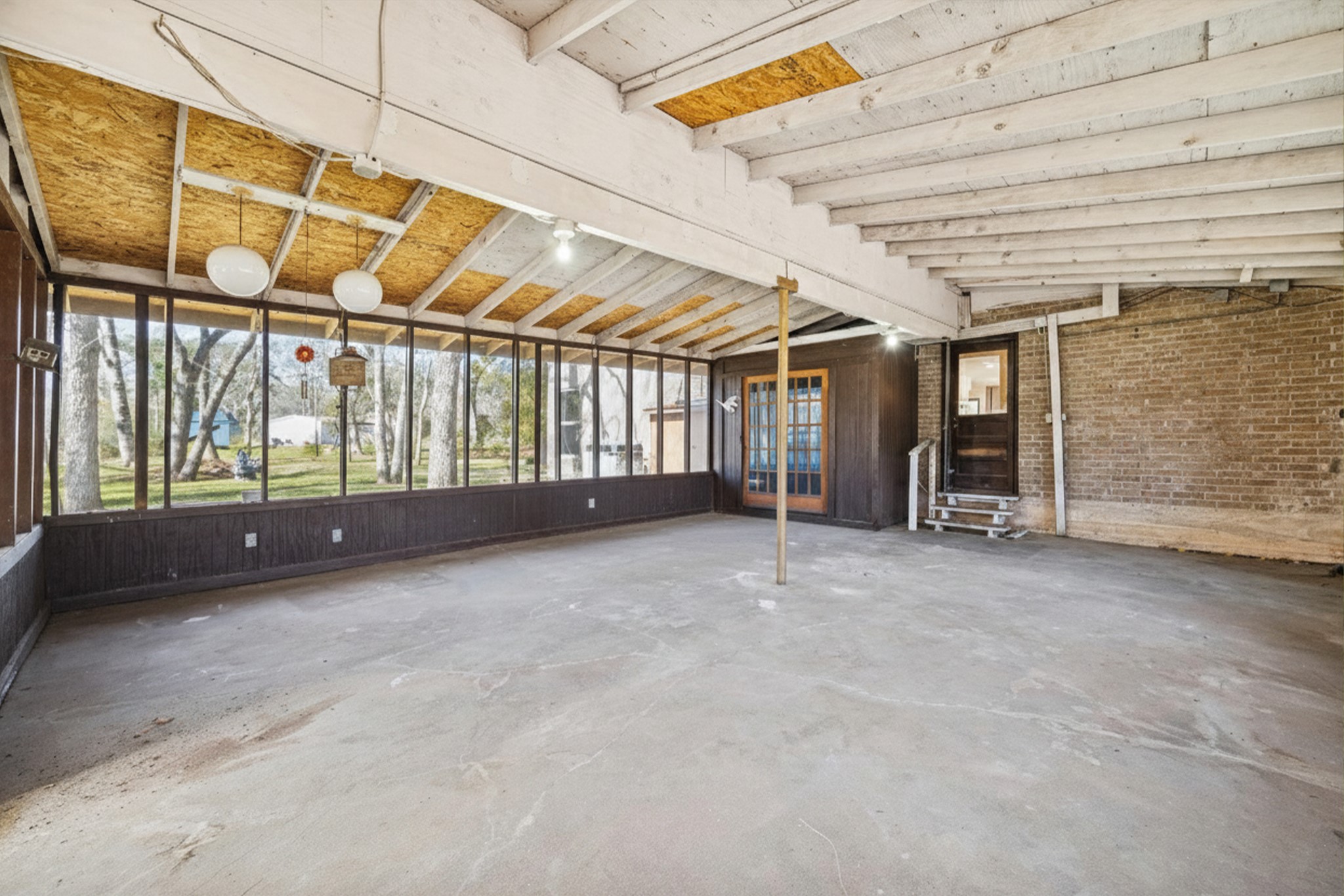 14311 Blidel Road Thompsons, TX 77469 - Photo 18 of 27 Alternate view of the covered patio showcasing generous square footage, rustic ceiling details, multiple access points, and views of the surrounding acreage.
