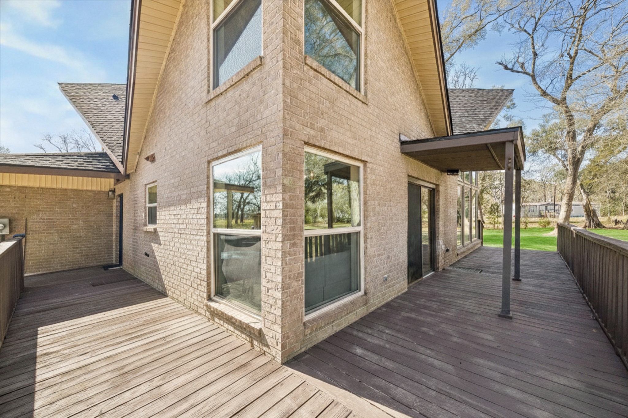 14311 Blidel Road Thompsons, TX 77469 - Photo 2 of 27 Rear deck view featuring multiple seating areas, wood decking, covered sections, and views of the surrounding acreage.