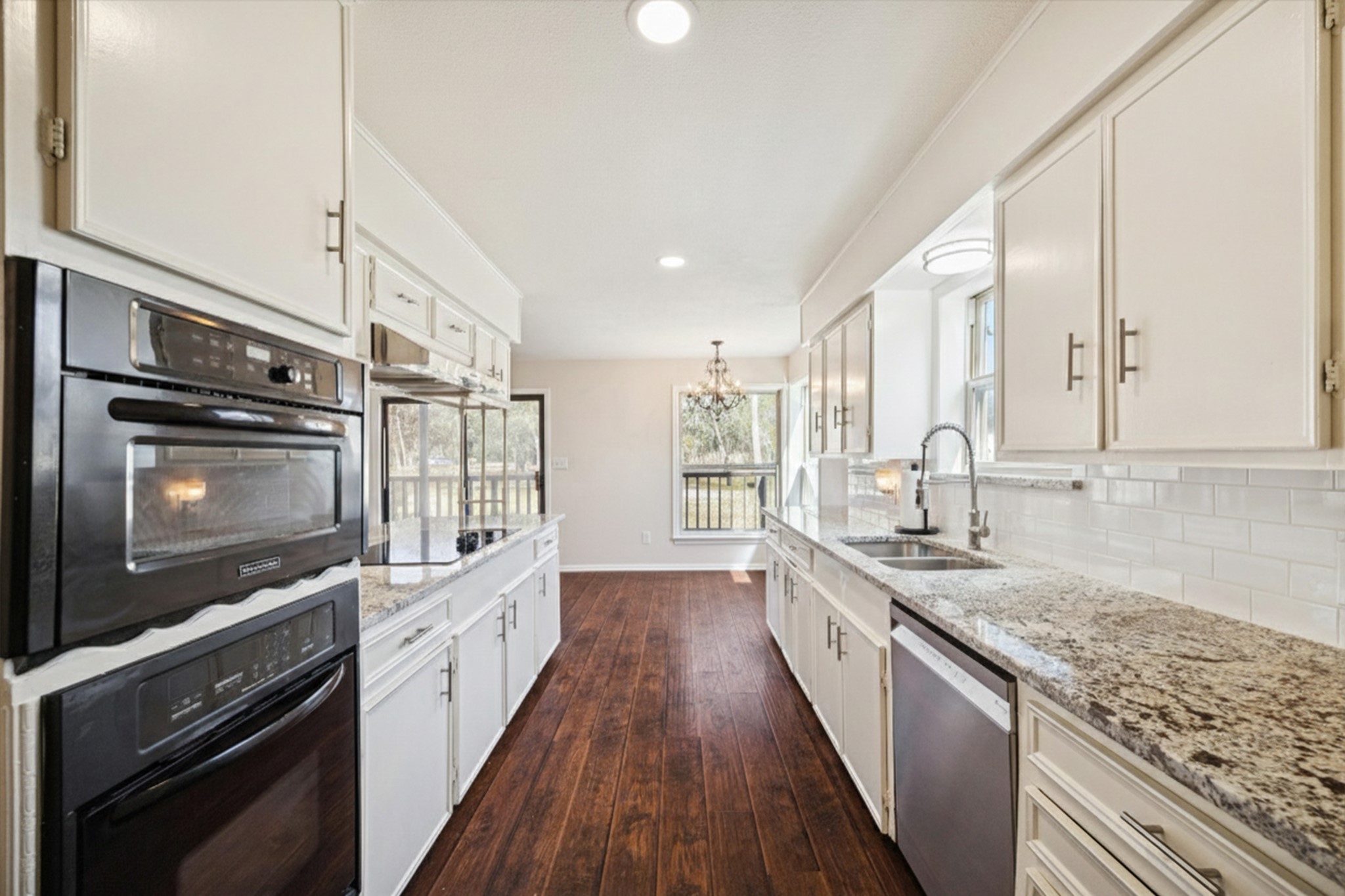 14311 Blidel Road Thompsons, TX 77469 - Photo 8 of 27 Galley-style kitchen view featuring granite countertops, white cabinetry, subway tile backsplash, built-in wall ovens, and upgraded flooring.
