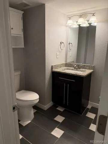 a bathroom with a granite countertop toilet sink and mirror
