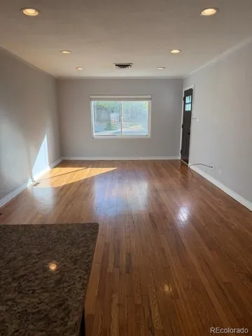 an empty room with wooden floor and window