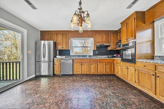 a kitchen with stainless steel appliances granite countertop a sink a stove a refrigerator cabinets and a window