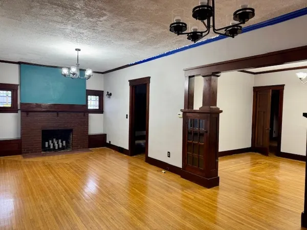 a view of a livingroom with a fireplace a chandelier and wooden floor