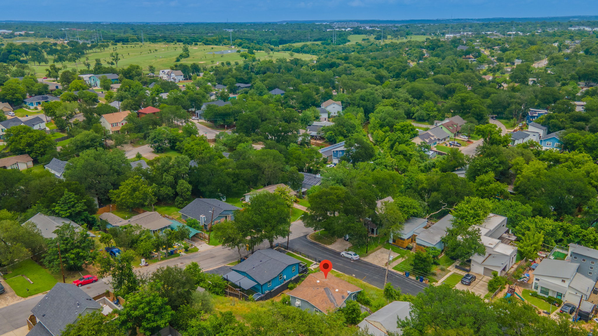 1410 Luna Street Austin, TX 78721 - Photo 3 of 5 An aerial perspective reveals a vibrant neighborhood nestled among abundant mature trees with a distant golf course view.
