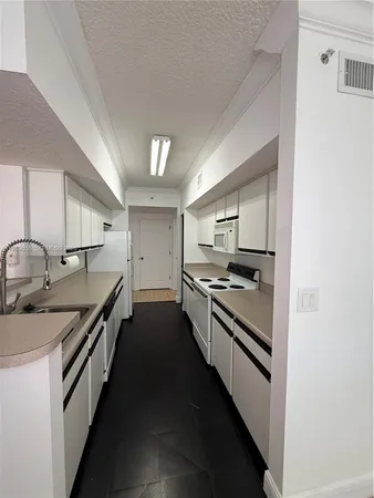 a view of a refrigerator in kitchen and an empty room