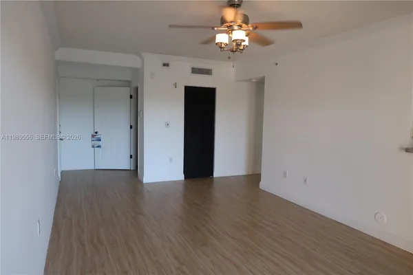 a view of an empty room with wooden floor and a window