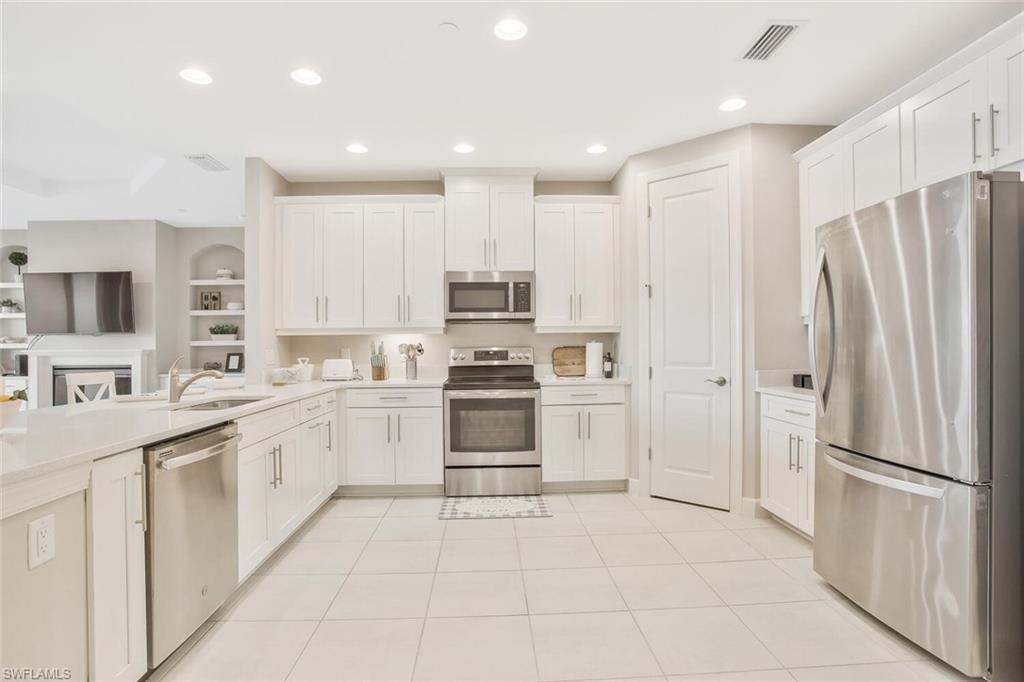9650 Montelanico Loop, Unit 103 Naples, FL 34119 - Photo 19 of 29 a kitchen with white cabinets and white appliances