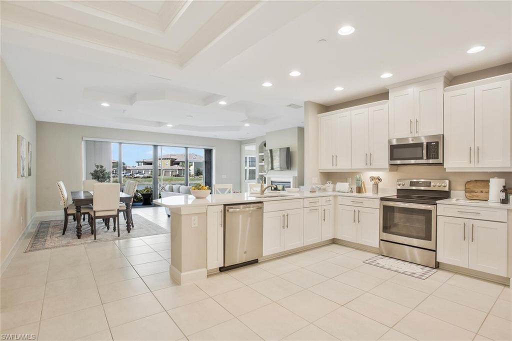 9650 Montelanico Loop, Unit 103 Naples, FL 34119 - Photo 5 of 29 a kitchen with white cabinets and appliances