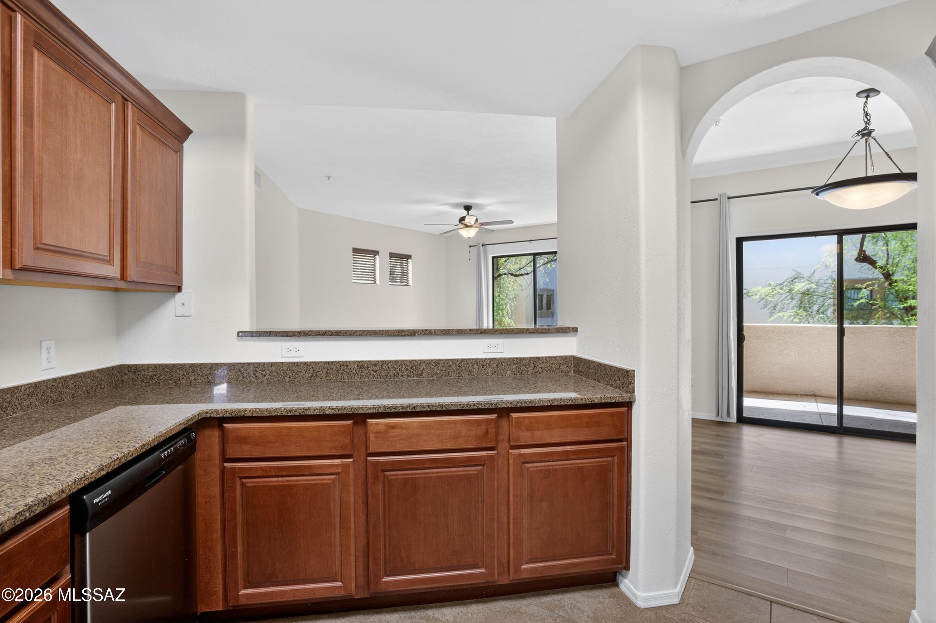 2550 East River Road, Unit 4204 Tucson, AZ 85718 - Photo 16 of 36 a kitchen with granite countertop a stove a sink and white cabinets with wooden floor
