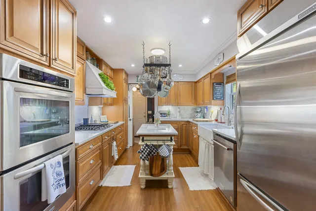 a kitchen with stainless steel appliances granite countertop a sink and wooden floor