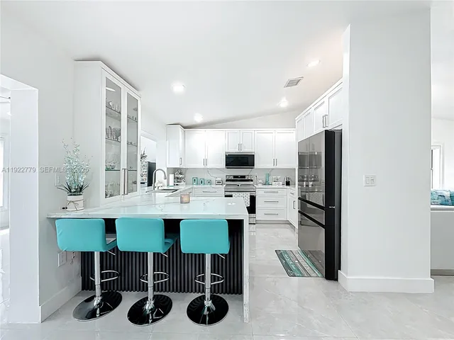 a kitchen with a sink chairs and refrigerator