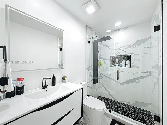 a bathroom with a sink toilet vanity and shower