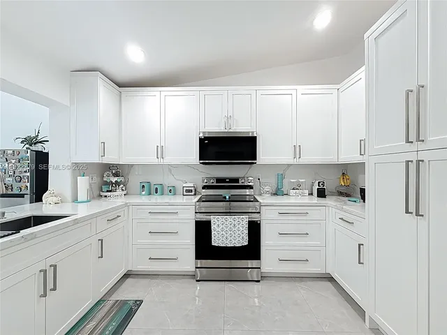 a kitchen with white cabinets and appliances