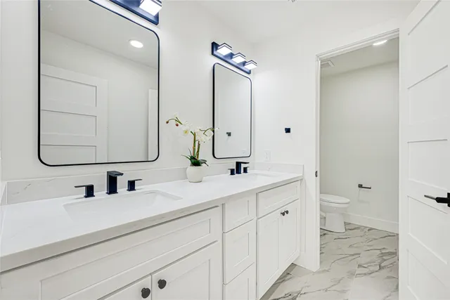 a bathroom with a double vanity sink mirror and toilet