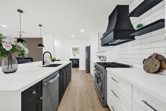 a kitchen with stainless steel appliances granite countertop a sink a stove and a wooden floors