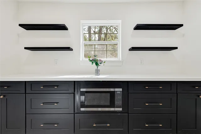 a view of cabinets a window and a potted plant on a dresser