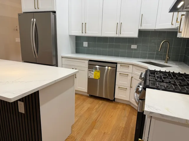 a kitchen with stainless steel appliances a sink a stove a refrigerator and cabinets