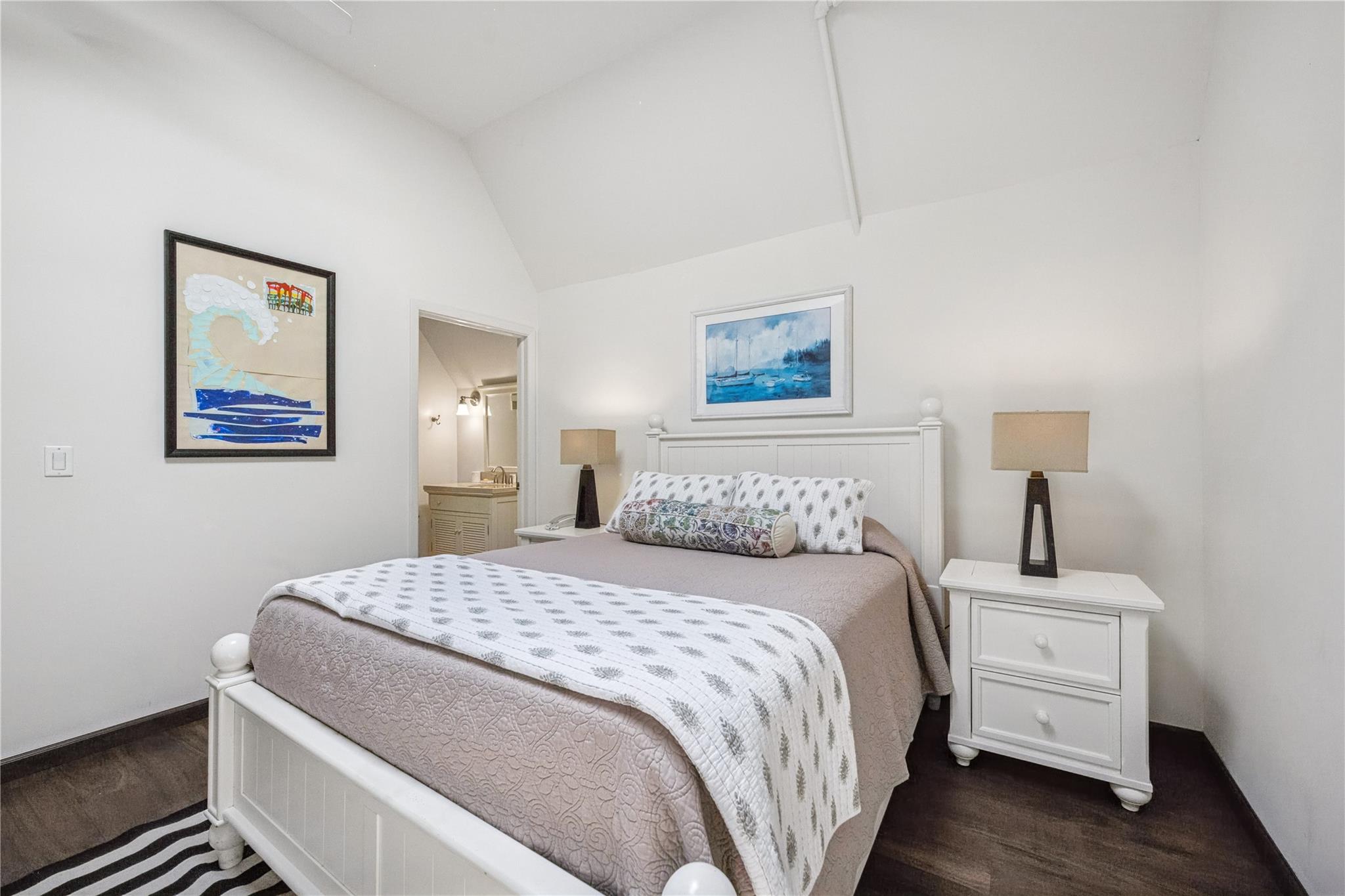236 Edgemere Street, Unit 427 Montauk, NY 11954 - Photo 14 of 42 Bedroom featuring dark wood-style floors, vaulted ceiling, and connected bathroom
