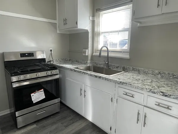 a kitchen with granite countertop a stove a sink and dishwasher with wooden floor