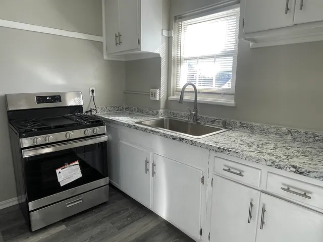a kitchen with granite countertop a stove a sink and dishwasher with wooden floor