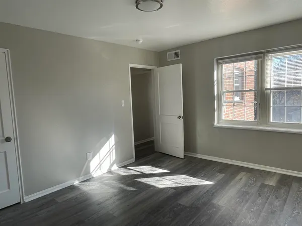 an empty room with wooden floor and windows