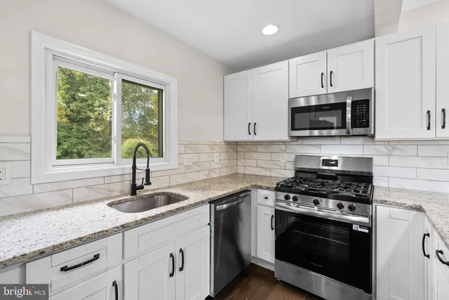 a kitchen with granite countertop a sink stainless steel appliances a window and a counter space