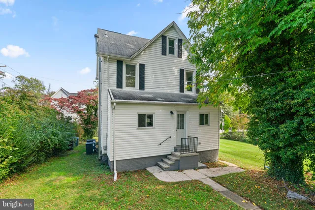 a view of a white house with a big yard and large trees